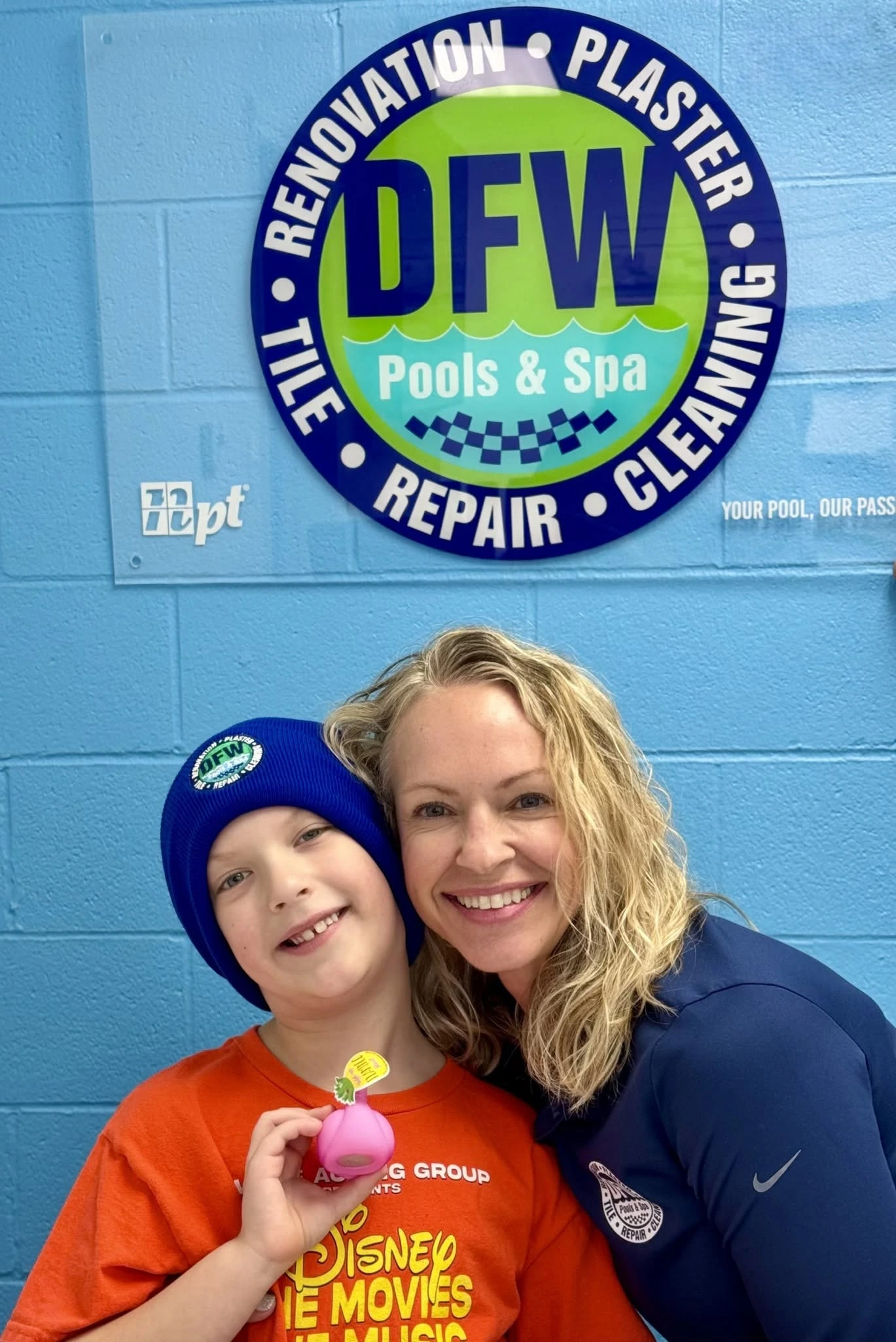 DFW Pools and Spa team member with the showroom wall sign
