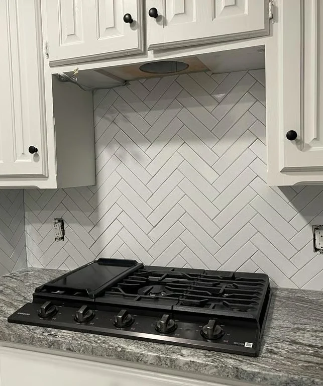 White herringbone kitchen backsplash behind a range