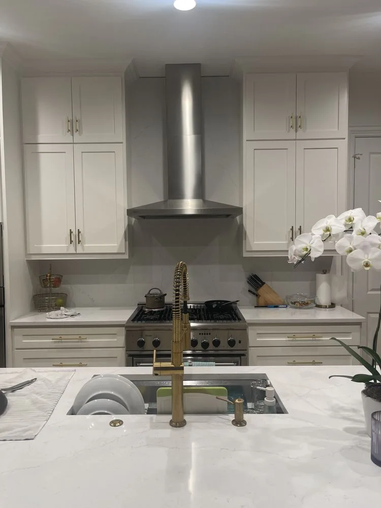 Modern white kitchen with brass fixtures and range hood
