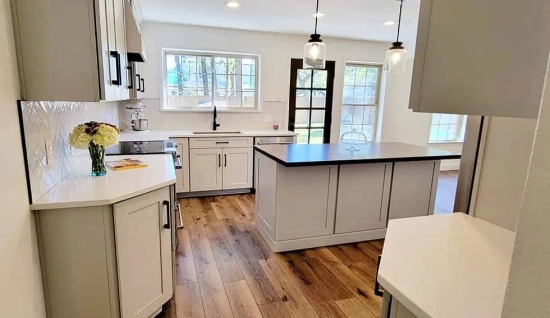 Kitchen remodel with greige cabinetry, black countertops, and a wood-top island