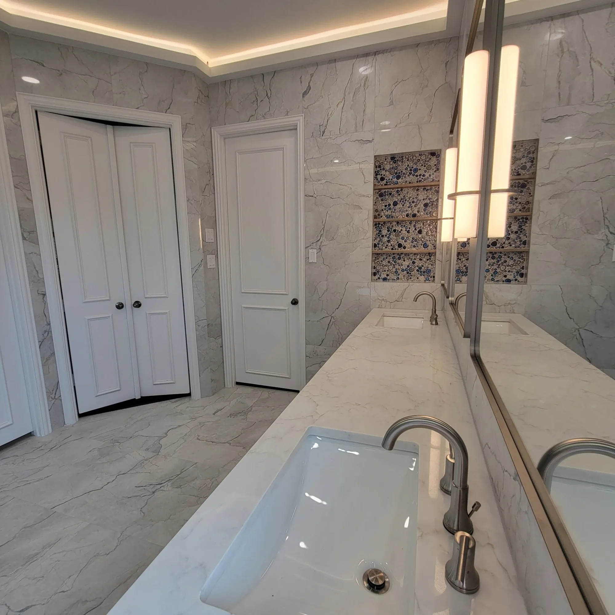 Primary suite hallway with walk-in closet and dual-sink vanity